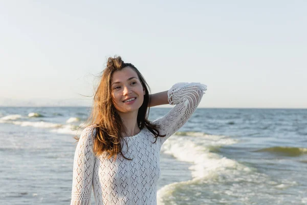 Portrait of young brunette woman looking away near blurred sea — Stock Photo