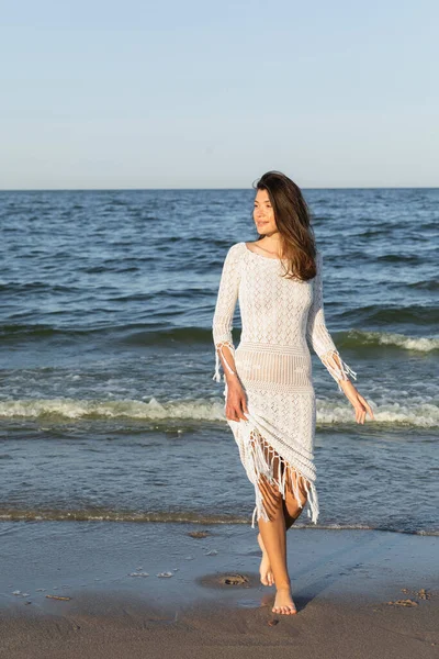 Barefoot woman in dress walking on sandy beach near sea — Stock Photo