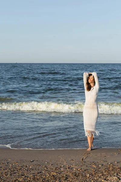 Barefoot woman walking on wet sand near sea on beach — Stock Photo