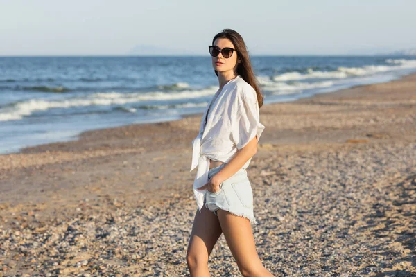 Woman in sunglasses and shirt standing on beach — Stock Photo