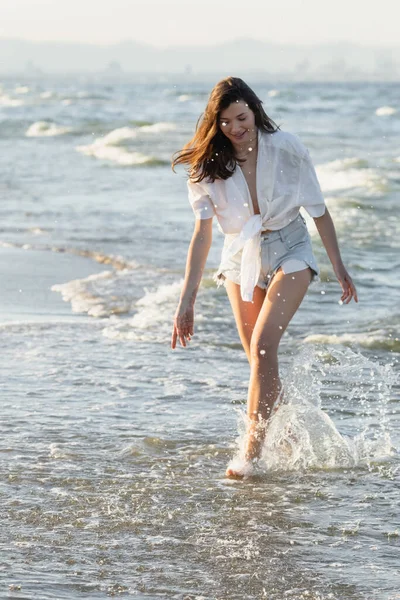 Молодая женщина в рубашке ходит по морскому побережью — стоковое фото