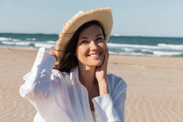 Portrait de jeune femme heureuse en chemise blanche et chapeau de soleil sur la plage — Photo de stock