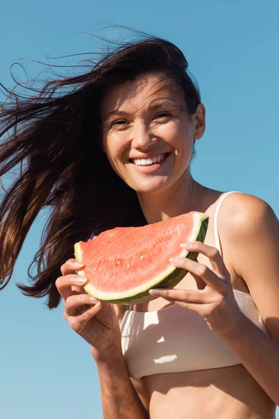 Glückliche junge Frau hält im Sommer geschnittene und saftige Wassermelonen in der Hand — Stockfoto