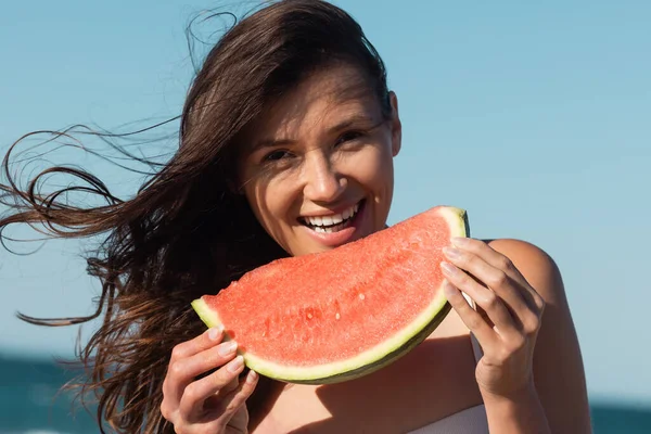 Porträt einer glücklichen jungen Frau, die im Sommer aufgeschnittene und saftige Wassermelonen hält — Stockfoto