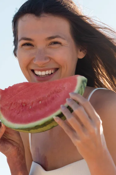 Close up of positive young woman holding sliced and juicy watermelon in summertime — Stock Photo