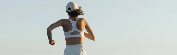 Back view of young sportive woman running near sea in summer, banner — Stock Photo