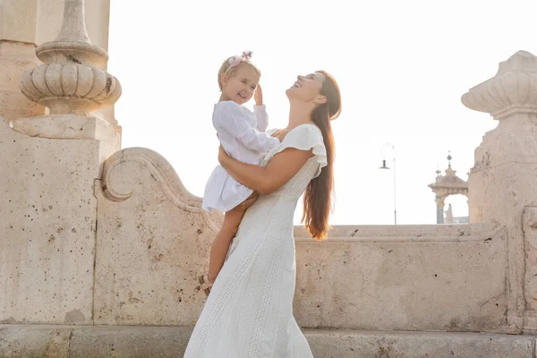 Donna positiva che tiene la figlia del bambino vicino al negozio Puente Del Mar bridge a Valencia — Foto stock