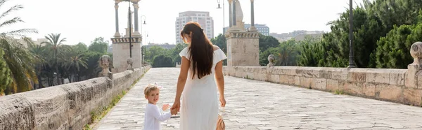 Smiling toddler child holding hand of mom while walking on Puente Del Mar bridge in Valencia, banner — Stock Photo