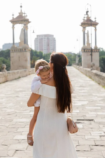 Brunette woman in dress holding child on Puente Del Mar bridge in Valencia — Foto stock