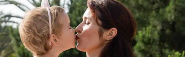Side view of brunette mother kissing baby daughter outdoors in Valencia, banner — Fotografia de Stock