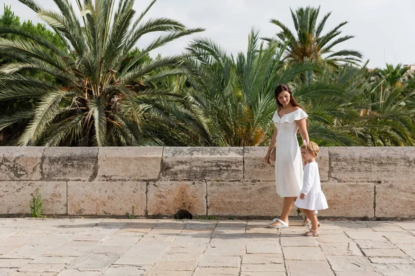 Woman and baby in summer dresses walking near palm trees in Valencia — Stock Photo