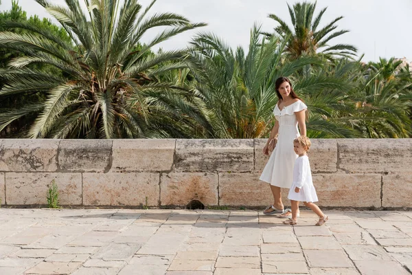 Child and mom in summer dresses walking outdoors in Valencia - foto de stock