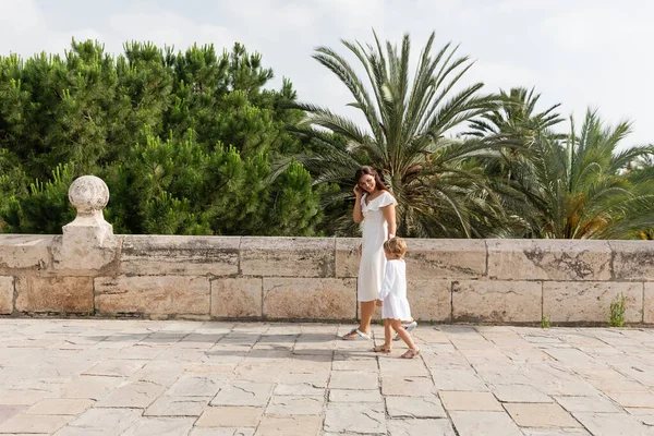 Smiling parent and child in summer dresses walking on bridge in Valencia — Stock Photo