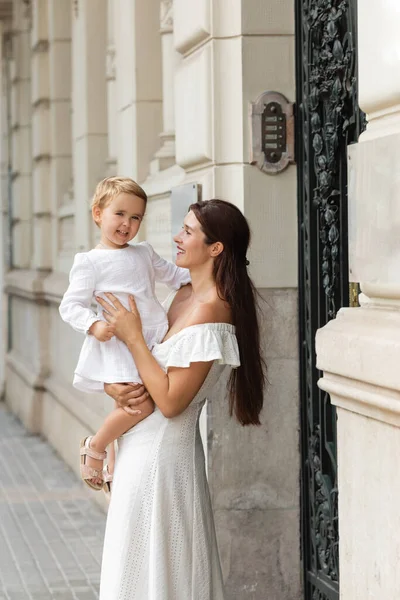 Женщина держит ребенка в летнем платье рядом со зданием в Валенсии — стоковое фото