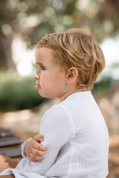 Side view of upset baby girl looking away outdoors - foto de stock