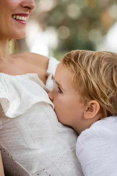 Side view of child sitting mom in summer dress outdoors — Stock Photo