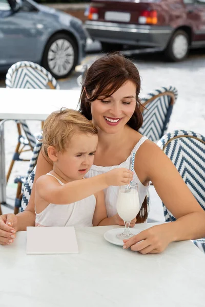 Smiling woman looking at baby daughter with drink in outdoor cafe in Spain — Stock Photo