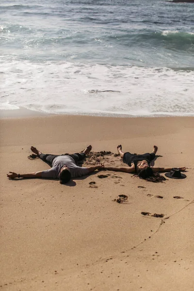 Casal deitado na areia molhada perto do oceano na praia em portugal — Fotografia de Stock