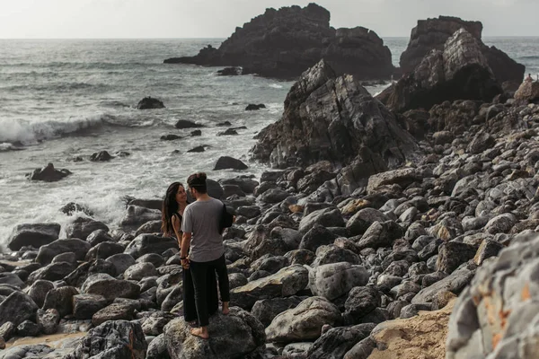 Tattooed woman smiling and looking at boyfriend near ocean in portugal — Stock Photo