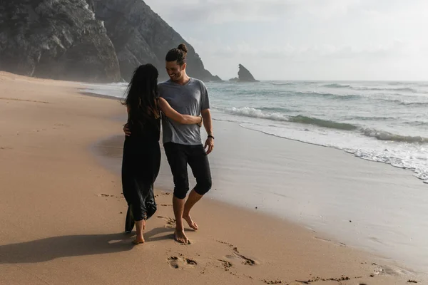 Happy man dancing with girlfriend in dress on wet sand near ocean — Stock Photo