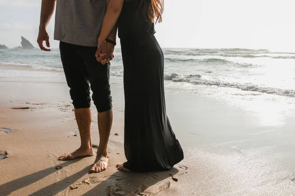 Abgeschnittene Ansicht eines Mannes, der Hand in Hand mit Freundin im Kleid in der Nähe des Ozeans steht — Stockfoto