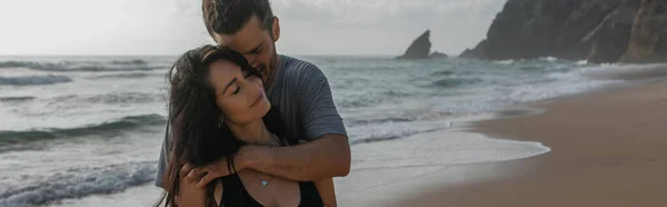 Happy man hugging smiling girlfriend near ocean in portugal, banner — Stock Photo