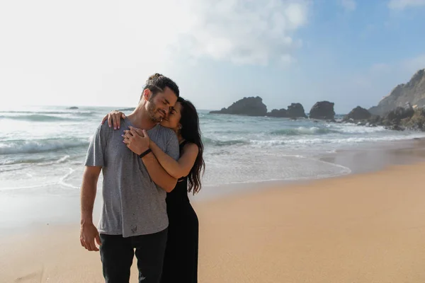 Happy woman in dress hugging cheerful boyfriend near ocean in portugal — Stock Photo