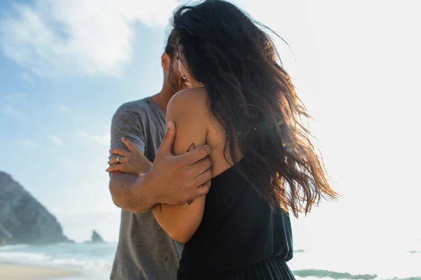 Bearded man hugging brunette girlfriend near ocean during vacation — Stock Photo