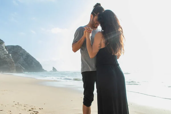 Happy bearded man holding hands with brunette girlfriend near ocean during vacation — Stock Photo