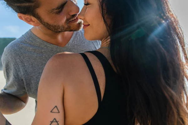 Bearded man smiling while kissing with tattooed and happy girlfriend — Stock Photo