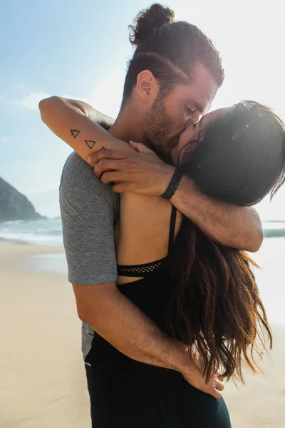 Barbudo homem beijos com tatuado namorada perto do oceano em portugal — Fotografia de Stock