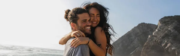 Cheerful man hugging tattooed woman on beach, banner — Stock Photo