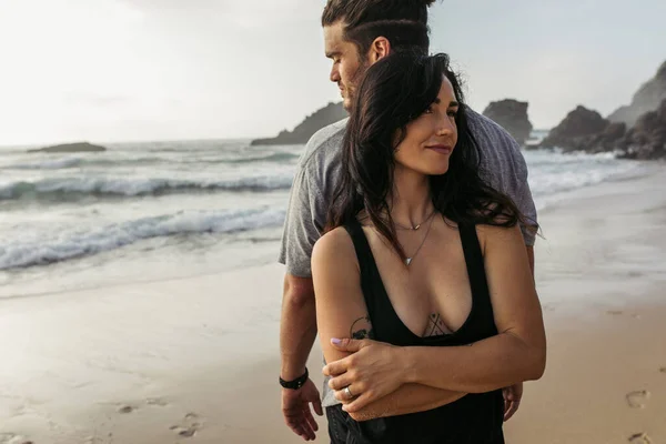 Tattooed woman standing back to back with bearded man near ocean — Stock Photo