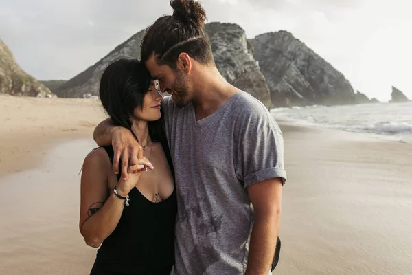 Cheerful bearded man and tattooed woman in dress holding hands near ocean — Stock Photo