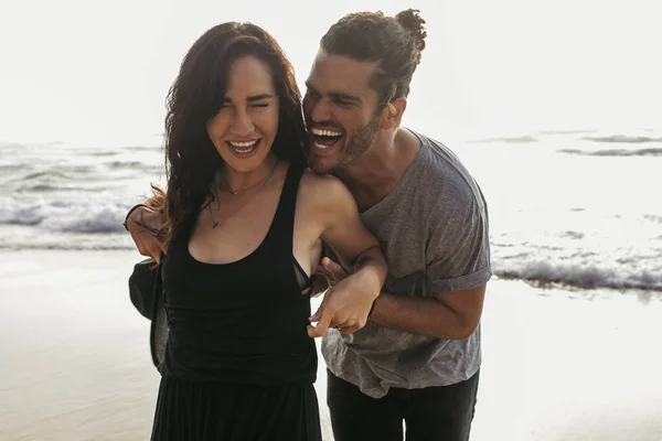 Allegro uomo ridere mentre solletico gioiosa fidanzata in abito vicino oceano in Portogallo — Foto stock