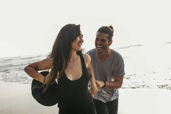 Fröhlicher Mann kitzelt lächelnde Freundin im Kleid mit Hut am Meer in Portugal — Stockfoto