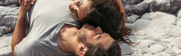 Top view of bearded man and woman with closed eyes lying on rocks, banner — Stock Photo