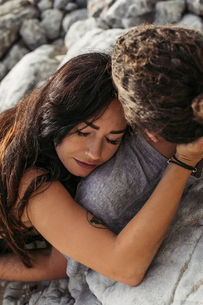 Tattooed woman with closed eyes and man lying together on rocky beach — Stock Photo