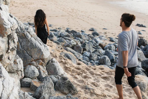 Bearded man walking behind woman on rocky beach in portugal — Stock Photo