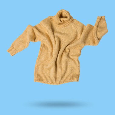 yellow knitted sweater flies, levitates, as if waving his arms, concept, on a blue background, casts a shadow.