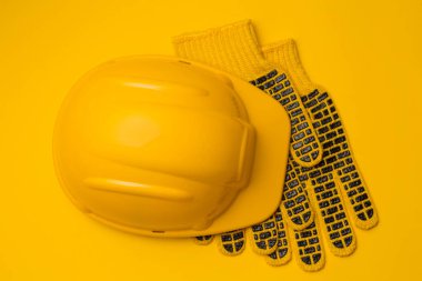 Sarı arka planda sarı miğfer ve koruyucu eldivenler, kafa ve el koruması, konsept