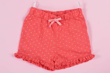 Çocuk kırmızı pamuğu şortu, pembe arka planda, yaz alışverişi konsepti