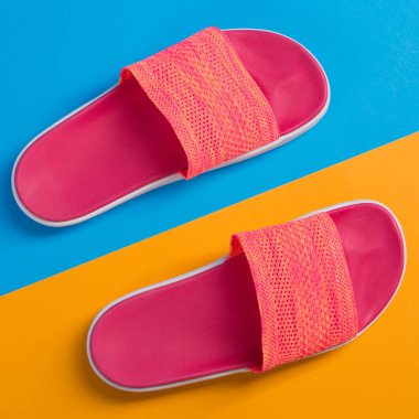 Mavi ve sarı arka planda pembe terlikler, yaz tatili ve seyahat kavramı