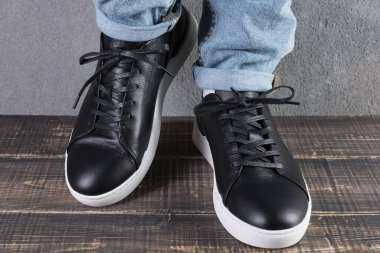 Beyaz tabanlı siyah deri ayakkabılı erkek bacakları, bir bacağı havada, konsept...