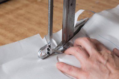 Kumaşı elektrikli bıçakla kesmek, erkek eli kumaşı tutmak, dikiş atölyesi, makro.