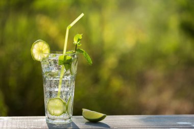 Açık havada yüksek bir bardakta naneli ve limonlu mojito içmek yeşilliğin arka planına karşı, kopyalama alanı