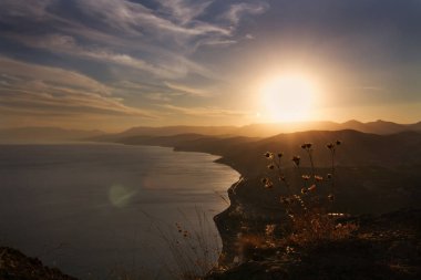 Dağlı ve denizli manzara, günbatımında büyük güneş, arka plan