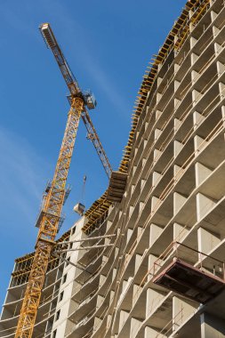 Sarı vinç inşaat halindeki evin yakınında çalışıyor, evin iskeletinin elementleri.