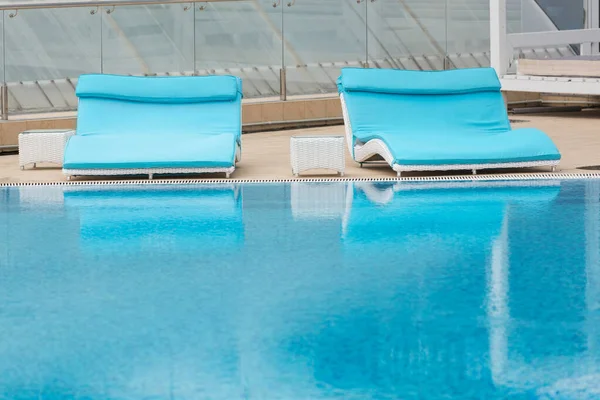 2つの広いターコイズデッキの椅子はプールの横にあり 水に反映されています — ストック写真