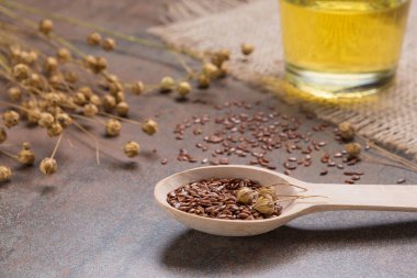 Ahşap kaşıkta keten tohumu ve grunge yüzeyde keten tohumu yağı, bez çuval bezi, yakın çekim.